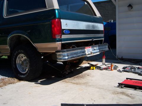 1996 Ford Bronco - The rear bumper of a Ford Bronco is removed, with tools and jacks visible on the concrete.
