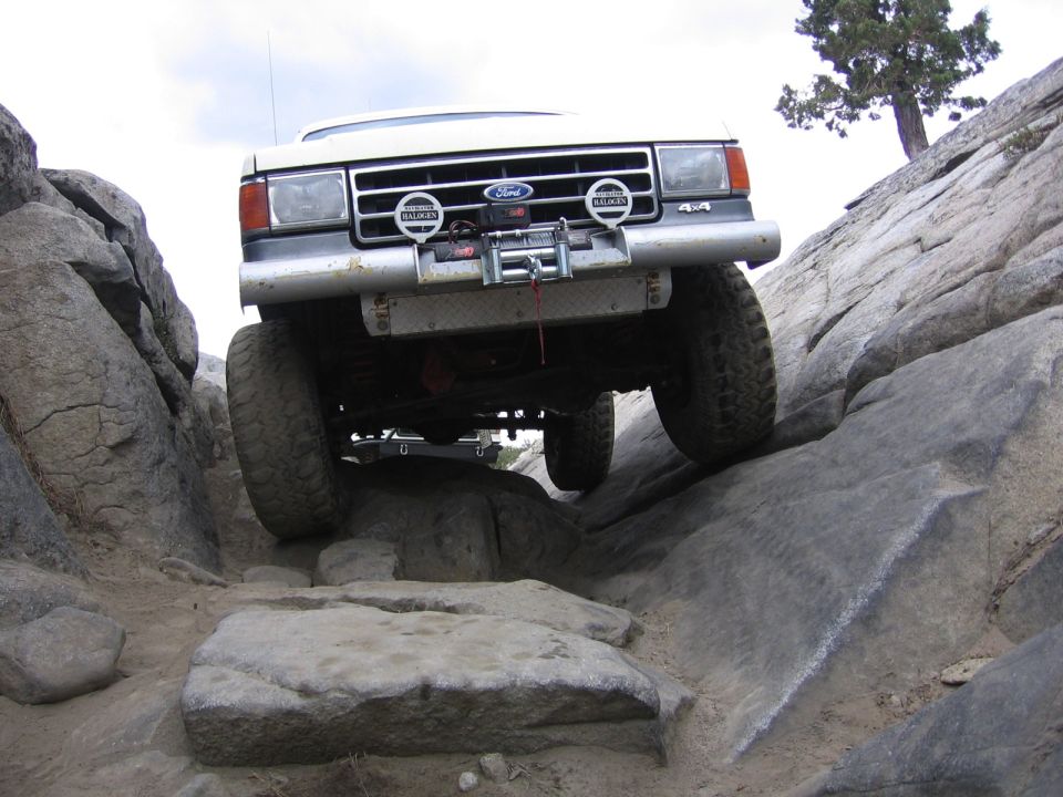 1991 Ford Bronco climbing over large rocks on a trail
