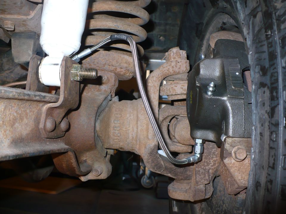 Braided stainless brake line on a solid front axle disc brake caliper