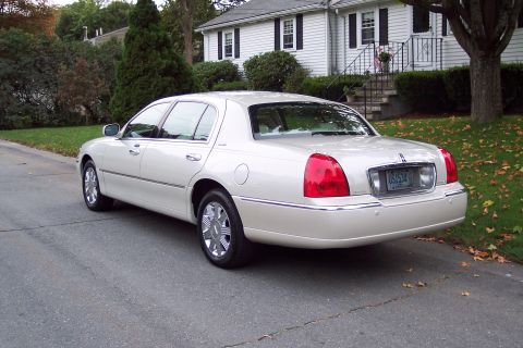 2001 Ford Crown Victoria - This Lincoln Town Car is parked on a street in front of a house with a lawn covered in fallen leaves.