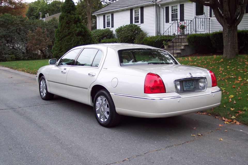 Rear view of a cream-colored Lincoln Town Car parked on a residential street