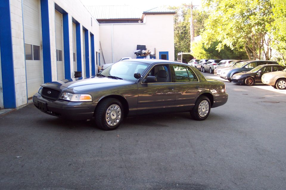 Dark gray 2001 Ford Crown Victoria 3q front view parked outside a building
