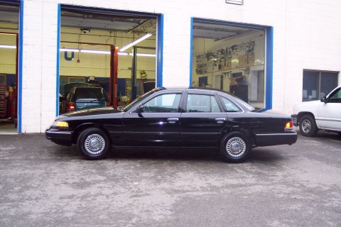 2001 Ford Crown Victoria - Black 2001 Ford Crown Victoria parked next to a white pickup truck outside a garage.
