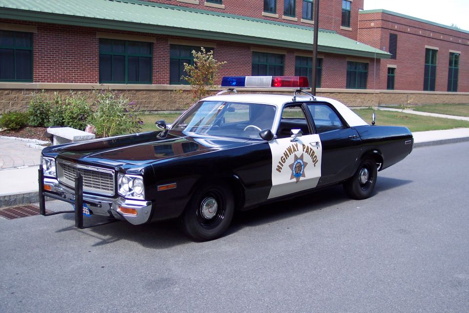 Black and white police car with "Highway Patrol" on the door, parked on asphalt