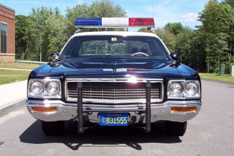 2001 Ford Crown Victoria - A police car with a light bar and push bumper is parked on a road.