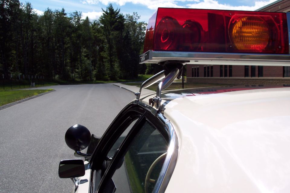 White police car with red and amber light bar, side view