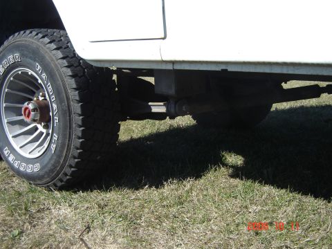 1993 Ford Bronco - Close-up of a vehicle's tire and suspension system, with grass visible underneath.