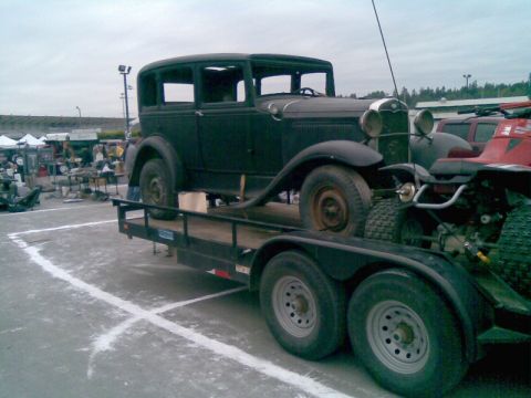 1969 Lincoln Continental - A dark-colored sedan is transported on a trailer, possibly at an outdoor event or swap meet.