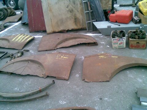 1969 Lincoln Continental - Assorted rusty car fenders and parts are displayed on the ground, some marked with numbers.