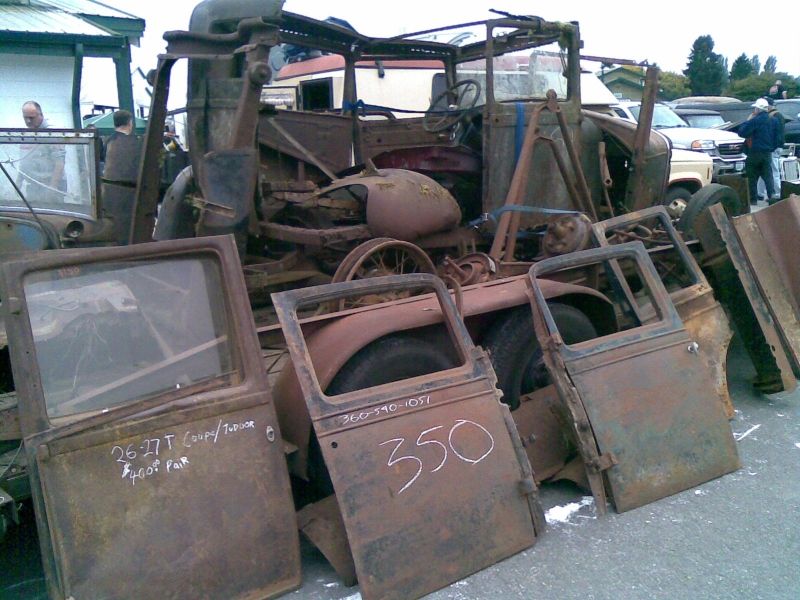 Pile of rusty car doors and a wrecked car body. One door says '26-27 T Coupe/Truck $400 Pair'. Another door has '350' written on it