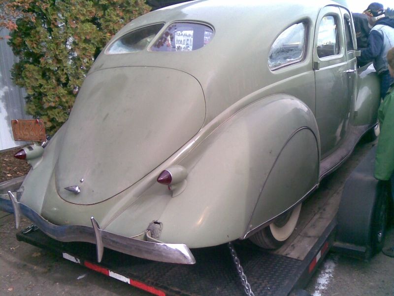 Pale green vintage sedan rear view, on a trailer