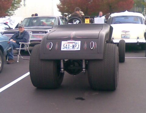 1969 Lincoln Continental - A custom hot rod with massive rear tires is parked next to other vehicles at an outdoor event.