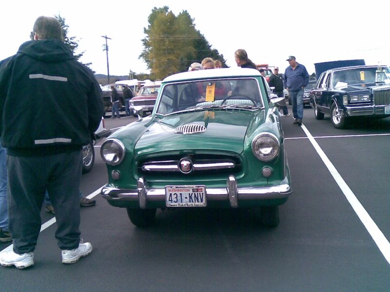 Green Nash Metropolitan with a white roof and chrome grille, parked at an outdoor event