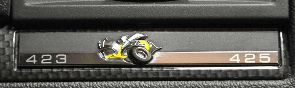 Chrome dash plate numbered 423 and 425 with yellow cartoon hot rod emblem centered