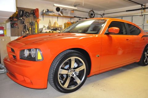 1973 Ford Ranchero - A bright orange Dodge Charger is parked in a garage with tools on the wall and a garage door overhead.