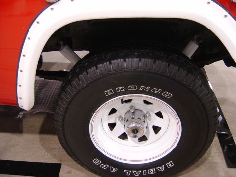 1996 Ford Bronco - Close-up of a red vehicle's wheel well, revealing the "BRONCO" tire branding.