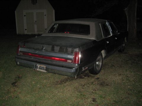 2000 Mercury Grand Marquis - A dark sedan with a vinyl roof is parked on a grassy area at night, with a shed in the background.