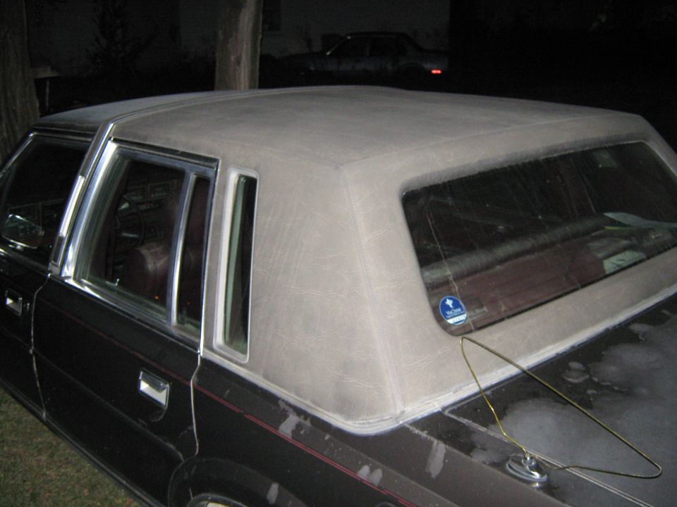 Car's vinyl top and rear window area. Another car is visible in the background
