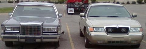 2000 Mercury Grand Marquis - Two sedans are parked side-by-side in a lot, with a semi-truck visible in the background.