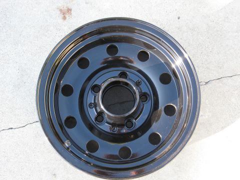 1986 Ford Bronco - Black steel wheel with 5x5.5 bolt pattern shown on concrete.