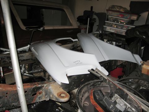 1986 Ford Bronco - Unidentified vehicle body parts and chassis components are stored in a garage setting.