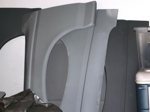 1986 Ford Bronco - Unidentified gray fender parts are stored indoors, possibly for a vehicle.