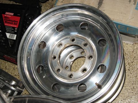 1986 Ford Bronco - Several aluminum wheels are stacked. A Craftsman wrench set is visible in the background.