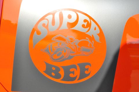 1973 Ford Ranchero - Close-up of the iconic Super Bee emblem, indicating a performance model, on a vehicle with orange and silver paint.