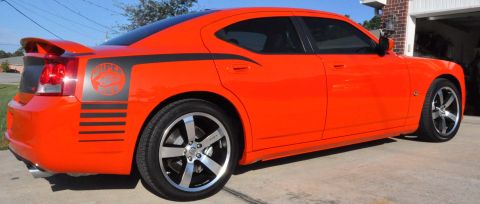 1973 Ford Ranchero - Orange Dodge Charger with black racing stripes and spoiler parked in driveway.