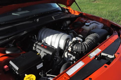 1973 Ford Ranchero - The engine compartment of an orange Dodge Challenger features a prominent 6.1L Hemi engine.