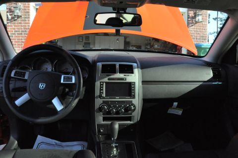1973 Ford Ranchero - The interior of a modern car is visible, with the hood open to reveal an orange underside and grey racing stripes.