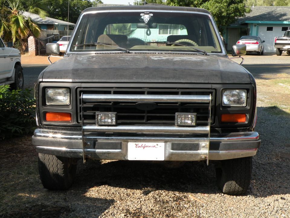 1980s Ford Bronco front with chrome grille and aftermarket lights. California license plate visible