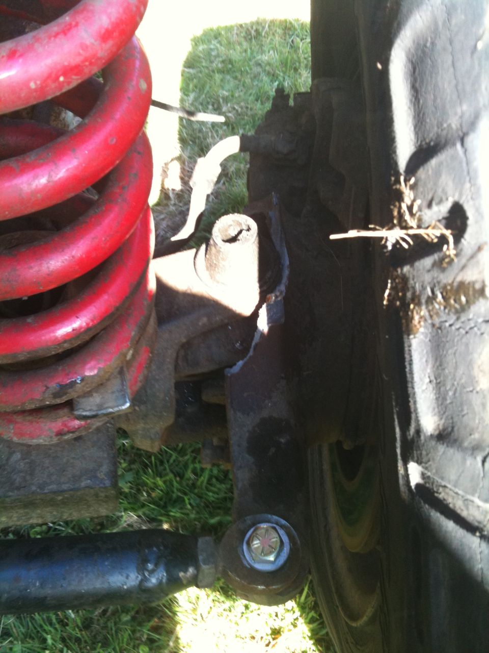 Close-up of a broken suspension component next to a red coil spring and tire