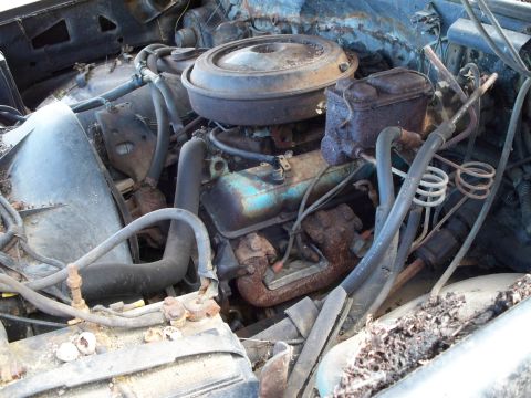 1988 Ford F-150 - Close-up view of a corroded engine bay, showing the engine block and various hoses.