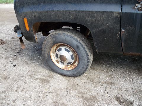 1988 Ford F-150 - Close-up view of a truck's front wheel and fender, revealing signs of wear and tear.