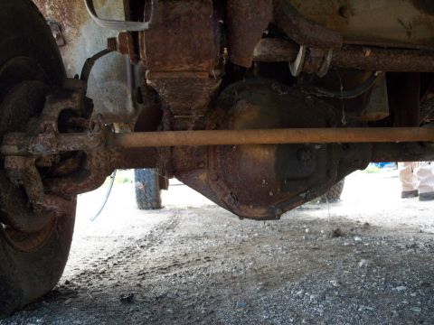 1988 Ford F-150 - Close-up view of the heavily rusted undercarriage of a truck, focusing on the differential and suspension parts.