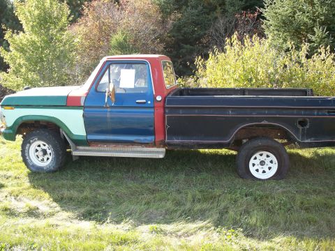 1988 Ford F-150 - This heavily modified Ford pickup truck displays a patchwork of colors and a flat tire.