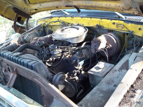 1988 Ford F-150 - The engine compartment of a yellow truck, showing the V8 engine and associated components.