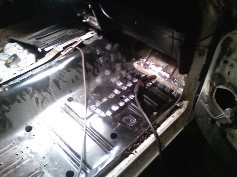 1969 Ford Mustang - Interior view of a car's floor, showing exposed metal, rust, and wiring, suggesting restoration work.