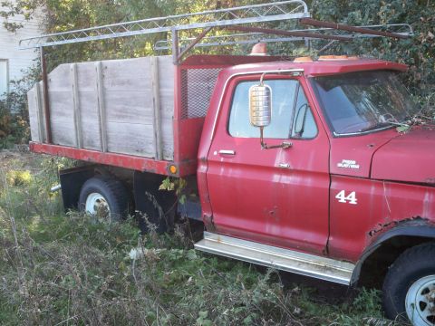1988 Ford F-150 - This 1988 Ford F-150 flatbed truck features a wooden bed and a utility rack, seen here in a rural setting.