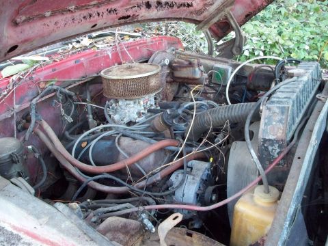 1988 Ford F-150 - The engine bay of a 1988 Ford F-150 shows its V8 engine, carburetor, and radiator, with visible signs of wear and tear.
