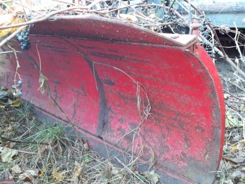 1988 Ford F-150 - A red snow plow sits outdoors, showing signs of wear and tear with surrounding vegetation.