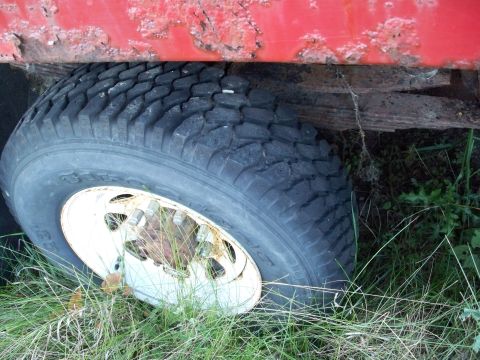 1988 Ford F-150 - Detail shot of a truck's wheel and suspension components, partially obscured by grass.