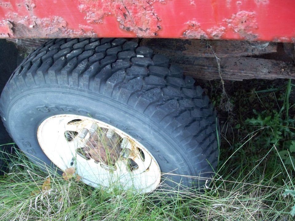 Close-up of a truck's wheel and leaf spring, with red bodywork above