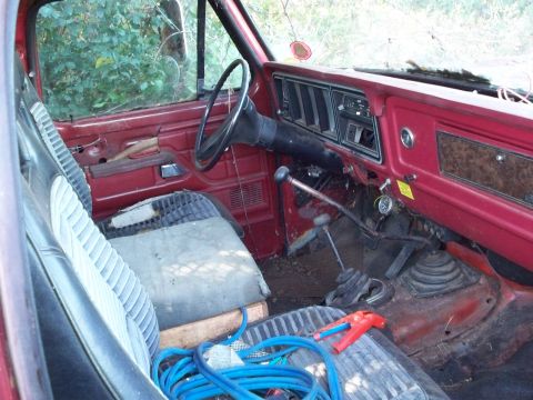 1988 Ford F-150 - The interior of an old truck shows its age with worn seats and a cluttered floor.