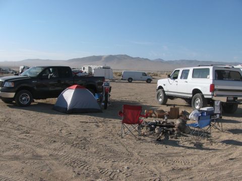 1996 Ford C-350 (Centurion Conversions) - Desert campsite with multiple vehicles and a tent under a clear blue sky.