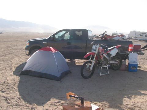 1996 Ford C-350 (Centurion Conversions) - A campsite is set up with a truck, tent, and dirt bikes in a desert landscape.