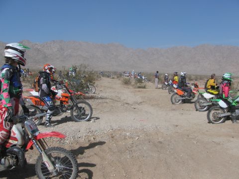 1996 Ford C-350 (Centurion Conversions) - Dirt bike race gathering in a desert environment with multiple participants and vehicles.