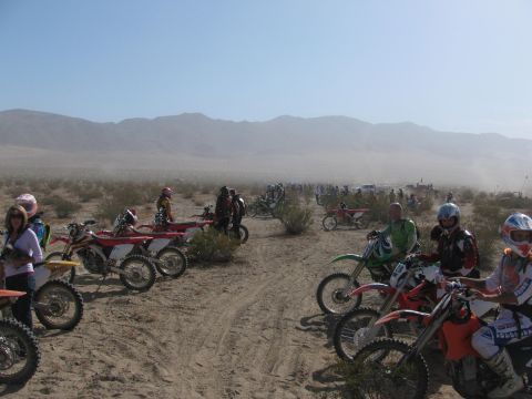 1996 Ford C-350 (Centurion Conversions) - A group of dirt bike riders and their motorcycles are gathered in a dusty desert environment.
