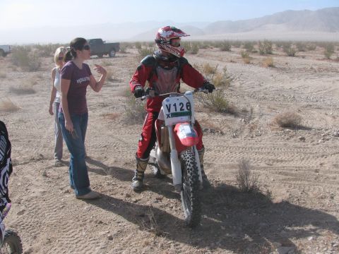 1996 Ford C-350 (Centurion Conversions) - A dirt bike rider prepares for an event in a dusty, arid environment with onlookers nearby spectators nearby.